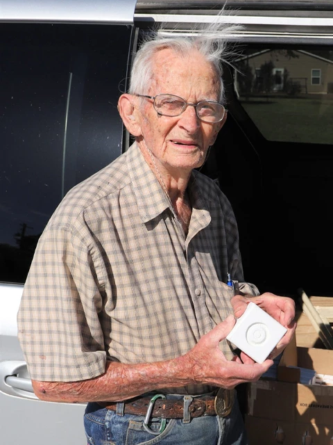 Don M. holding a rosette corner block in front of his van.