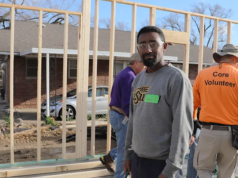 Andy is standing with volunteers at a wall-raising event.