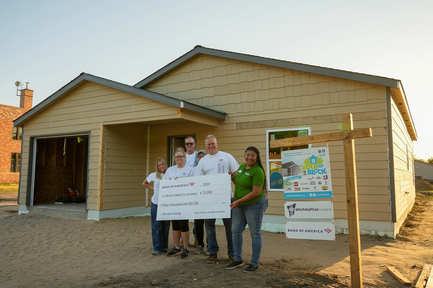 Bank of America volunteers standing behind a Bank of America check with Danielle of Wichita Habitat.