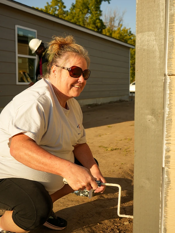 Cindy of Bank of America paints the side of a home.