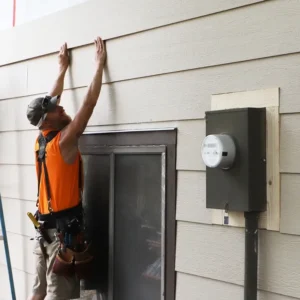Home repair employee holding onto siding of a home.