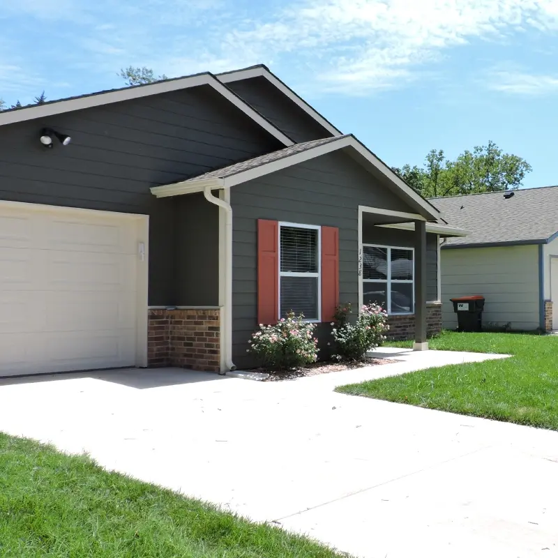Exterior view of a home with a driveway and small flower bushes in the front yard.