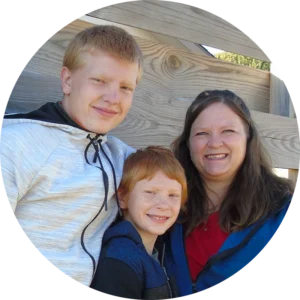 Family partner Cherity and her sons standing in front of a built fence.