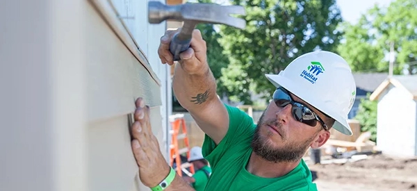 A volunteer hammering a wall.