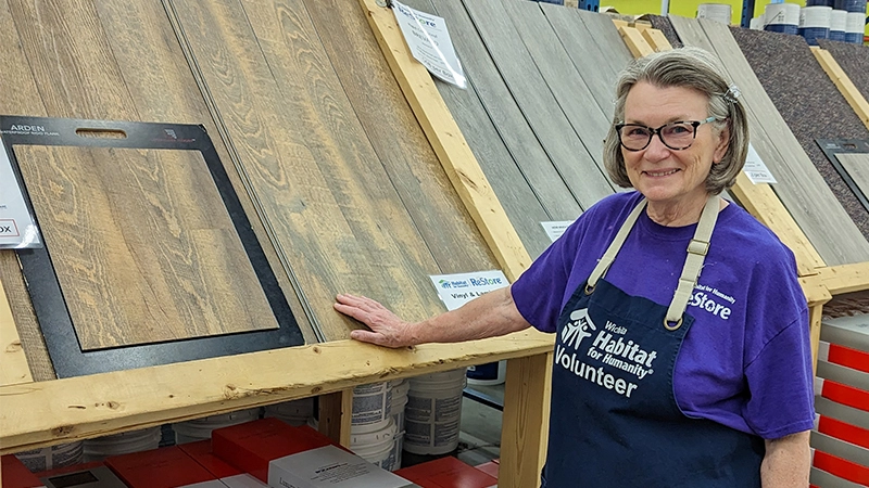 Core volunteer Connie posing in front of the flooring material section.