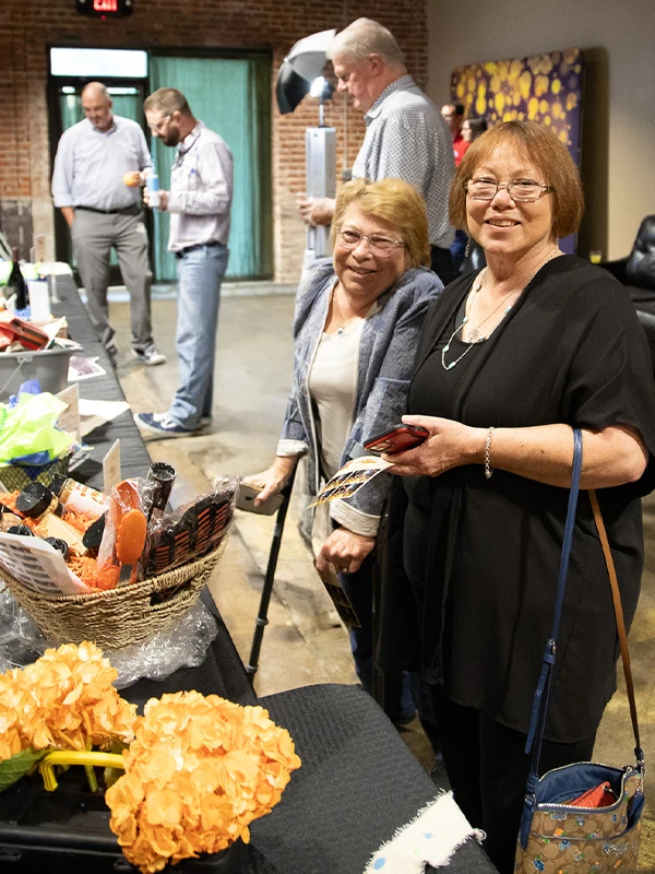 Two ladies looking at silent auction items at a Raise the Roof event.