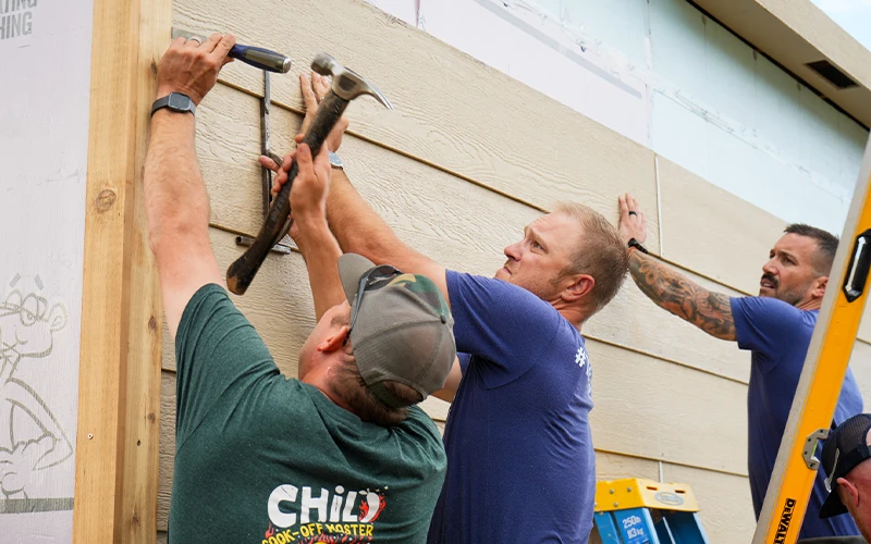 A group of volunteers putting siding up.
